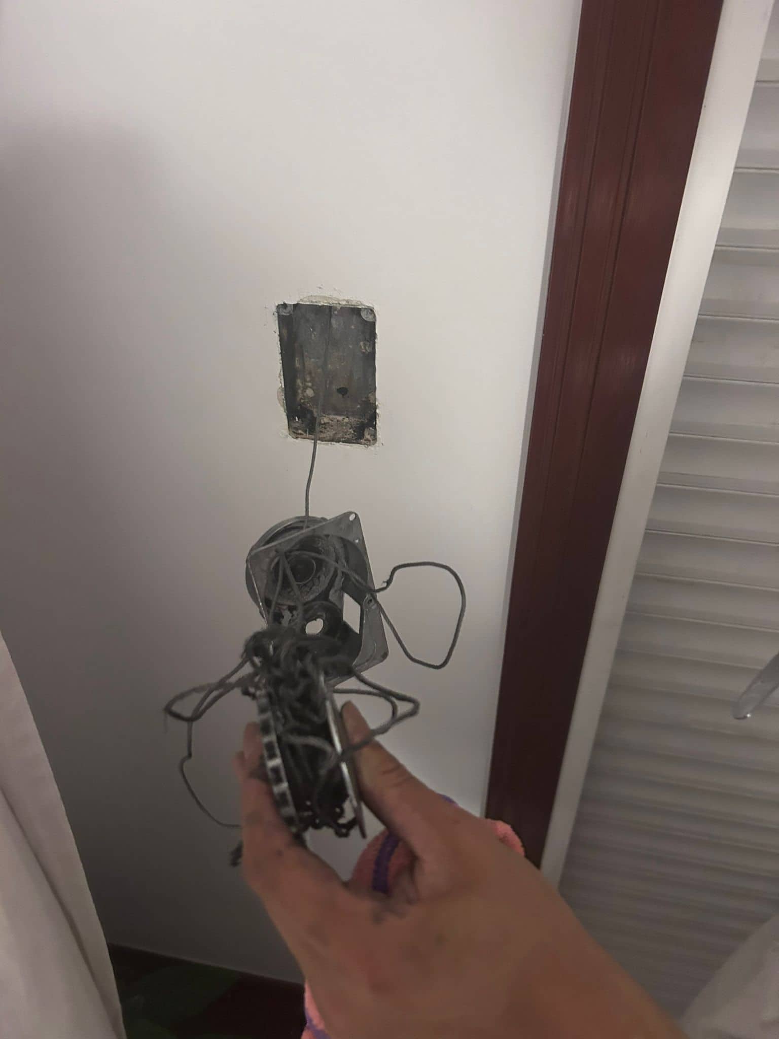 Recogedor de persiana desmontado con la cinta partida, junto al hueco vacío en la pared